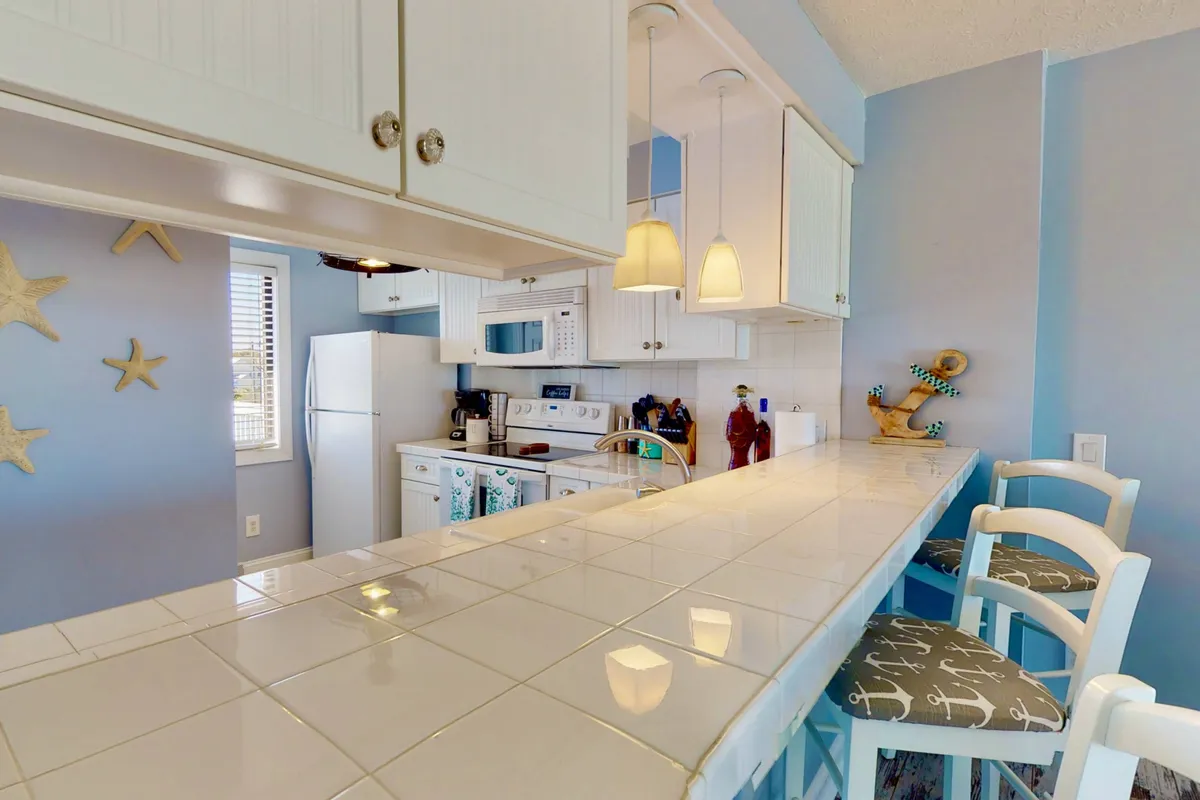A spacious kitchen island with stools, decorative starfish, and a range of contemporary appliances. The open layout allows for socializing or supervising family activities while preparing food.