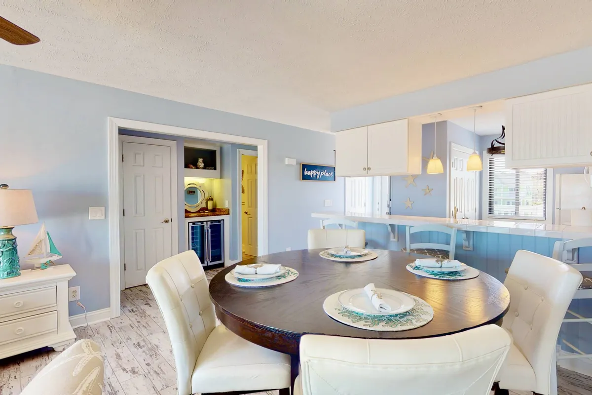 A cozy, intimate dining area with a round table, blue accent walls, and direct sightlines to the kitchen. The space is well-lit and designed for family gatherings and memorable mealtimes.